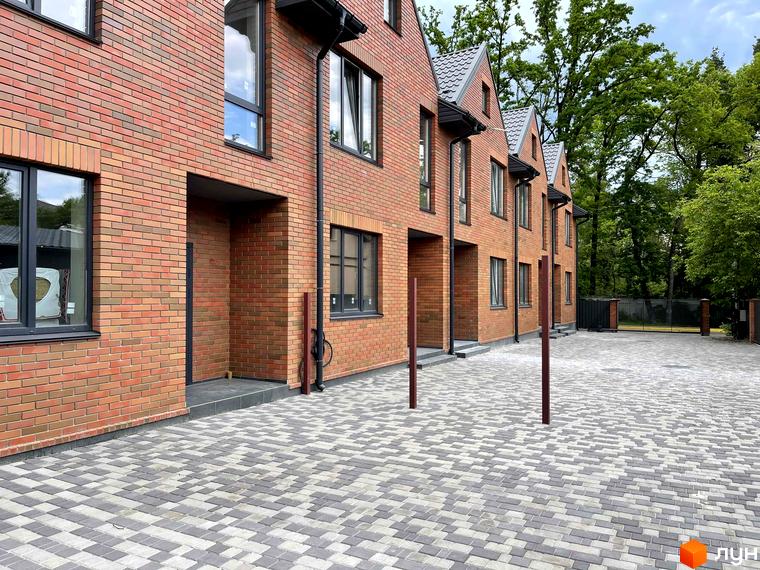 Таунхауси BRIGHTON GARDEN з червоної цегли з сірим дахом та бруківкою перед будинками. Зовнішній вигляд будівель та прибудинкова територія.