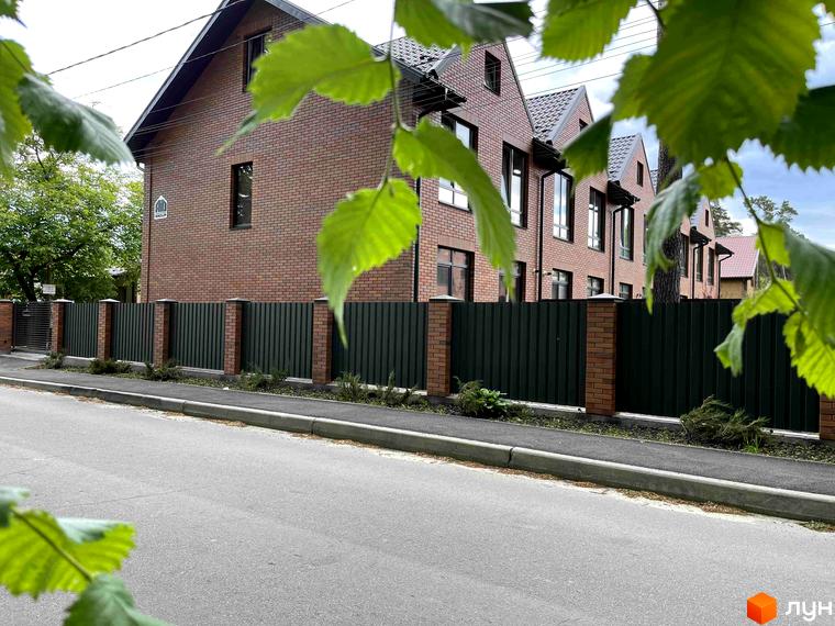 Таунхауси ELEGANT: цегляні фасади, зелені металеві паркани та бруківка біля дороги. Будівельний проєкт з доглянутою прибудинковою територією.