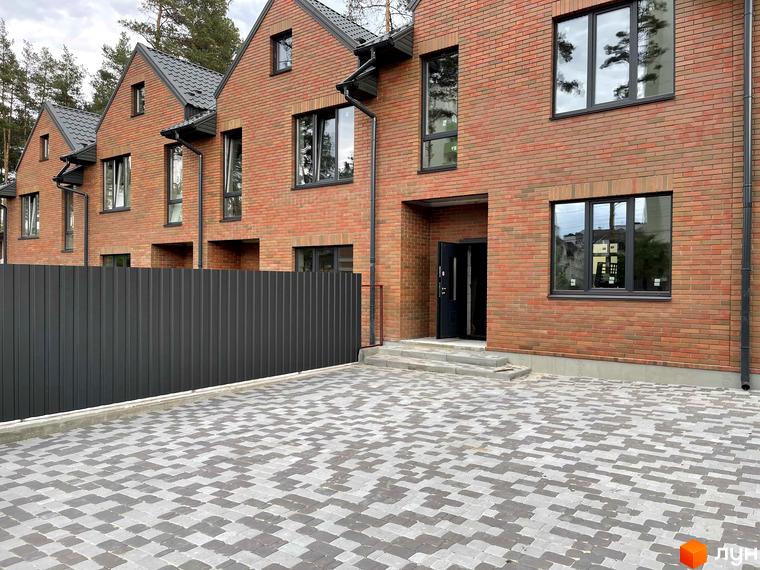 Таунхауси ELEGANT з червоної цегли з сірим дахом та вікнами. Перед будинками вимощена сіра бруківка та встановчена сіра огорожа.