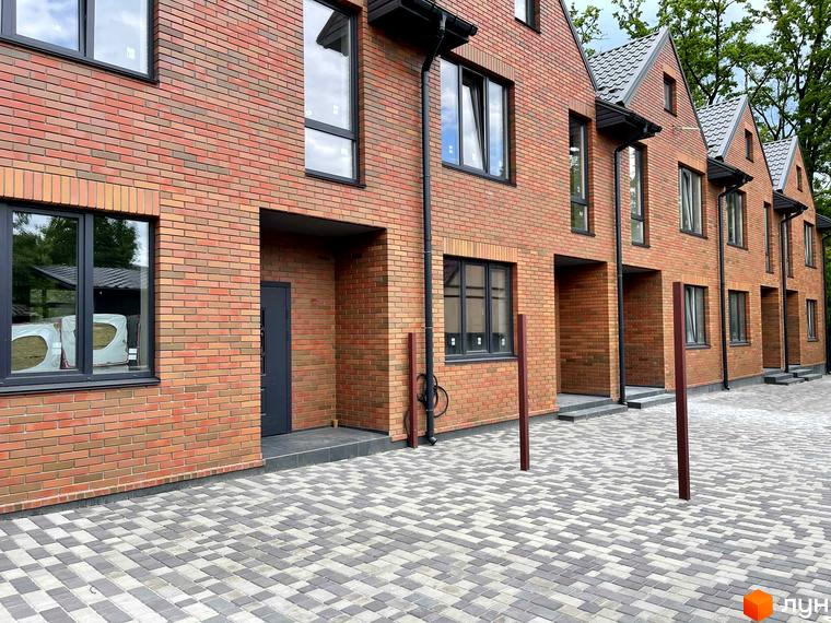 Таунхауси ELEGANT з цегляними фасадами та темними вікнами. Прибудинкова територія викладена бруківкою сірого та світлого кольорів.