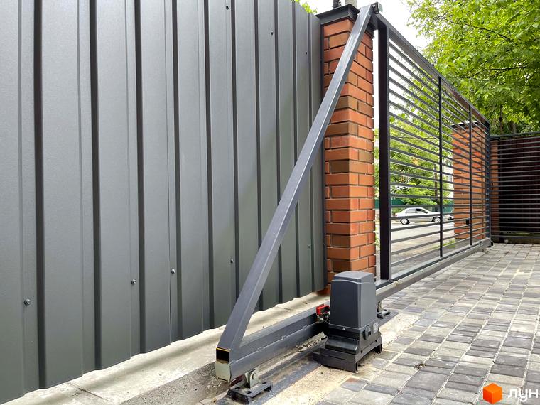 Автоматичні ворота та паркан з металопрофілю житлового комплексу Таунхауси ELEGANT. Бруківка та зелені насадження біля будинку.