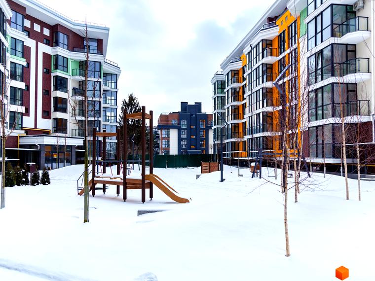 Зовнішній вигляд новобудови ЖК Лісова казка 2 з яскравими фасадами та зимовим подвір'ям з дитячим майданчиком. Сучасна архітектура та затишна прибудинкова територія.