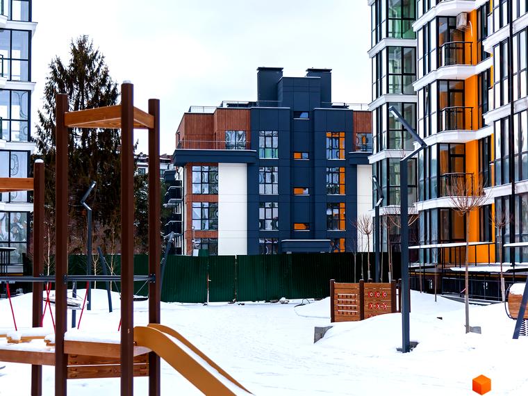 Зовнішній вигляд новобудови ЖК Лісова казка 2 з дитячим майданчиком та засніженою територією. Сучасна архітектура та комфортна прибудинкова територія.