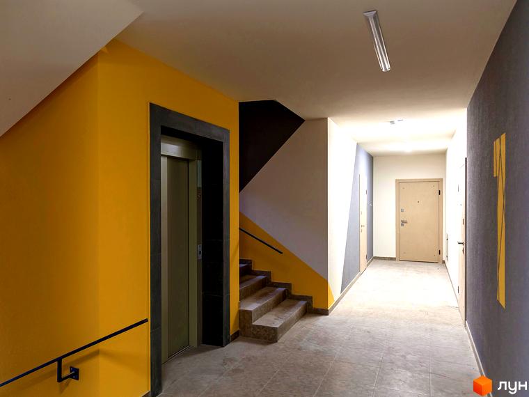 Сучасний під'їзд з ліфтом та сходами в ЖК Лісова казка 2. Вхідна група з яскравими жовтими та сірими акцентами.