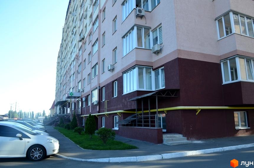 Зовнішній вигляд будинку житлового комплексу Софіївська Слобідка з парковкою та зеленими насадженнями на прибудинковій території.