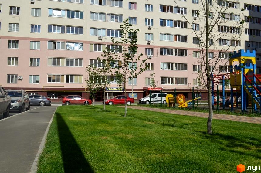Зовнішній вигляд будинку житлового комплексу Софіївська Слобідка з парковкою та прибудинковою територією з дитячим майданчиком.