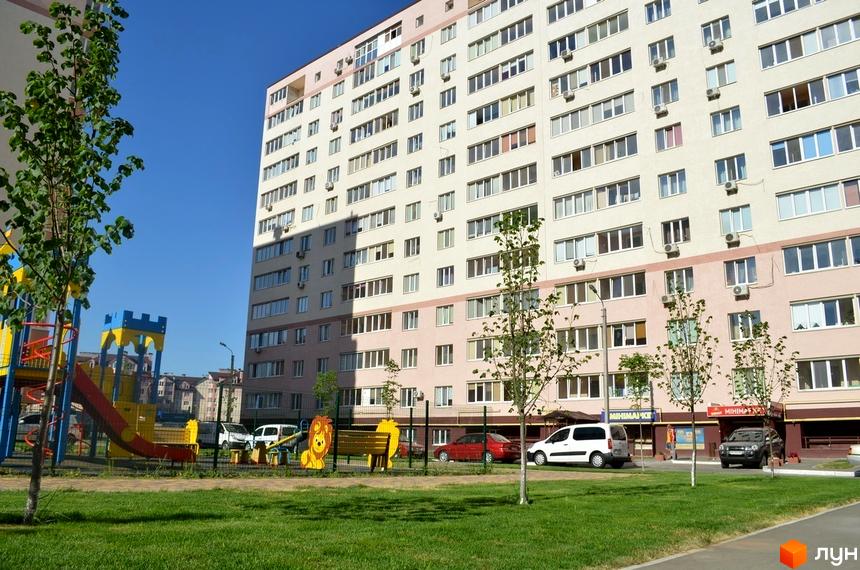 Житловий комплекс Софіївська Слобідка: багатоповерховий будинок з численними вікнами та кондиціонерами, поруч дитячий майданчик та зелена зона.