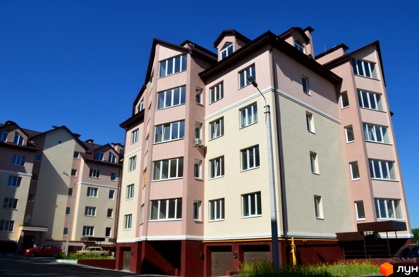 Житловий комплекс Софіївська Слобідка - багатоповерхові будинки з рожевим та бежевим фасадом, великими вікнами та темними дахами. На прибудинковій території видно автомобілі та зелені насадження.