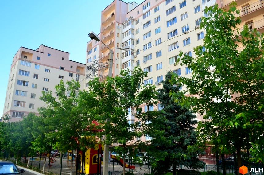 Житловий комплекс Софіївська Слобідка: багатоповерхові будинки з балконами та кондиціонерами, зелені дерева та дитячий майданчик на прибудинковій території.