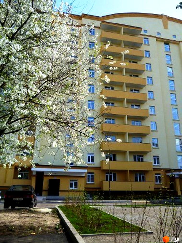 Житловий комплекс Яблуневий з жовтою фасадною частиною та балконами, оточений зеленими насадженнями і квітучими деревами.