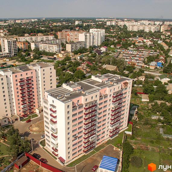 Житловий комплекс Нове Життя. Двоколірні багатоповерхові будинки з балконами та прибудинковою територією з дитячим майданчиком.