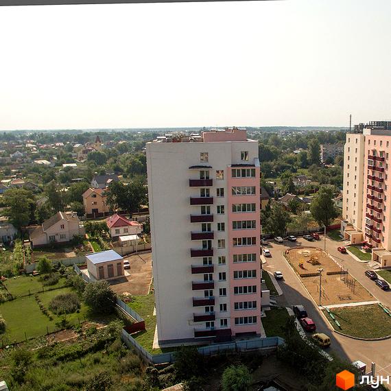 Житловий комплекс Нове Життя: багатоповерховий будинок з рожевими та білими фасадами, балконами та прибудинковою територією з дитячим майданчиком.