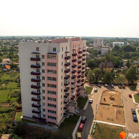 Новобудова ЖК Нове Життя з рожевими та білими фасадами, численними балконами. Поруч розташований дитячий майданчик та парковка.