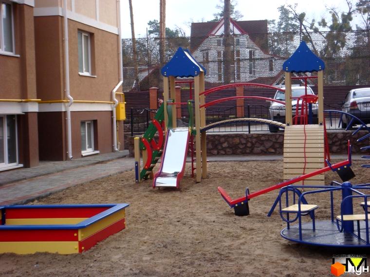 Зовнішній вигляд будинку житлового комплексу Квартал на 'Київській' з дитячим майданчиком та прибудинковою територією.