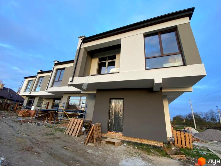 Новобудова на вул. Київська, 9 з сірим та білим фасадом, великими вікнами та будівельними матеріалами на території.