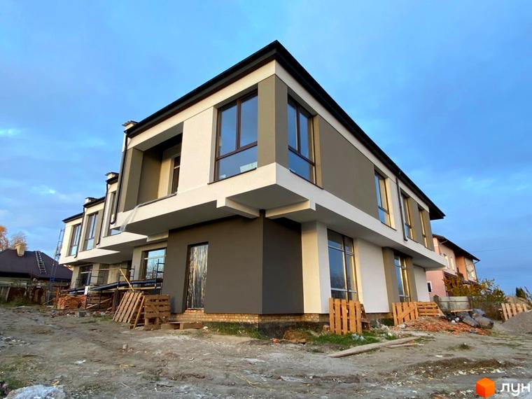 Зовнішній вигляд новобудови на вул. Київська, 9. Будинок має сіро-білий фасад з великими вікнами. Територія навколо будинку облаштована будівельними матеріалами.