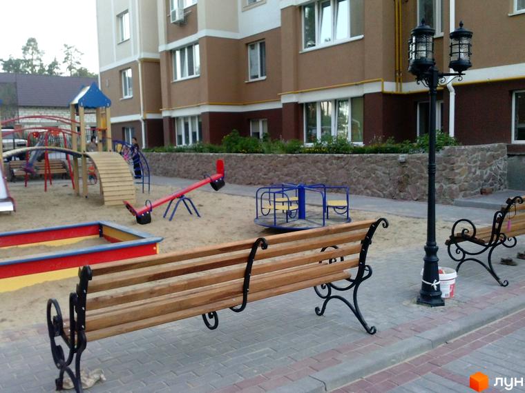Житловий комплекс Квартал на 'Київській' з ігровим майданчиком та лавками на прибудинковій території.
