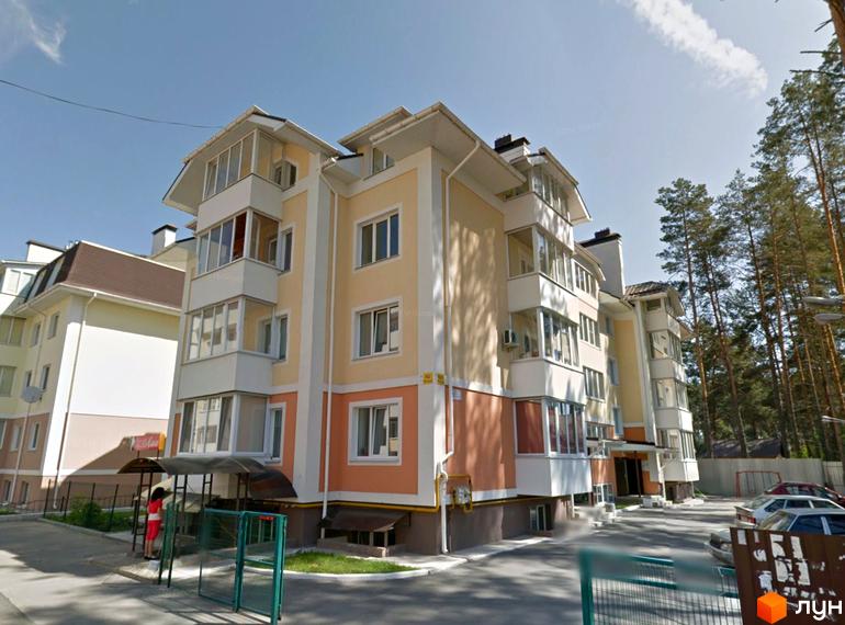 Житловий комплекс на вул. Лісова, 4д: будинок світло-жовтого та персикового кольорів з балконами. Поруч парковка та сосновий ліс.