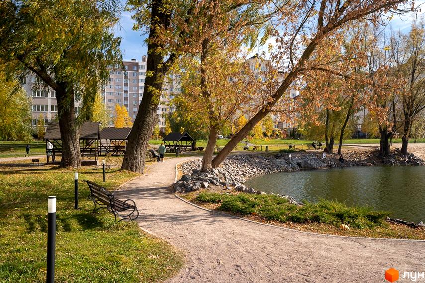 Житловий комплекс Озерний Гай (Гатне) з багатоповерховими будинками та доглянутою прибудинковою територією. Парк з озером, альтанками та доріжками.