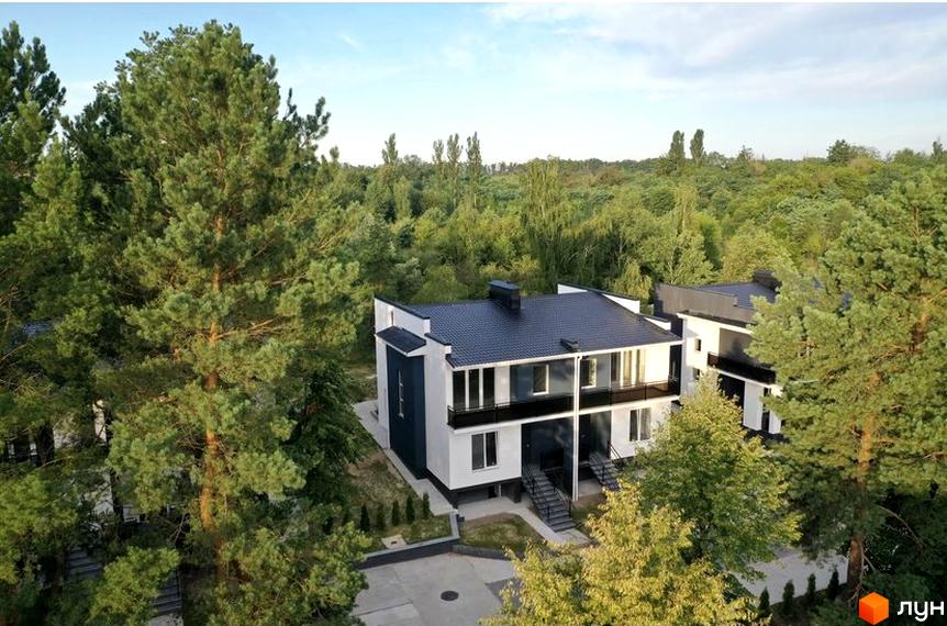 Котеджне містечко КМ Терещенські Озера: двоповерхові будинки з чорними дахами та білими фасадами, розташовані серед високих сосен та зелених дерев.