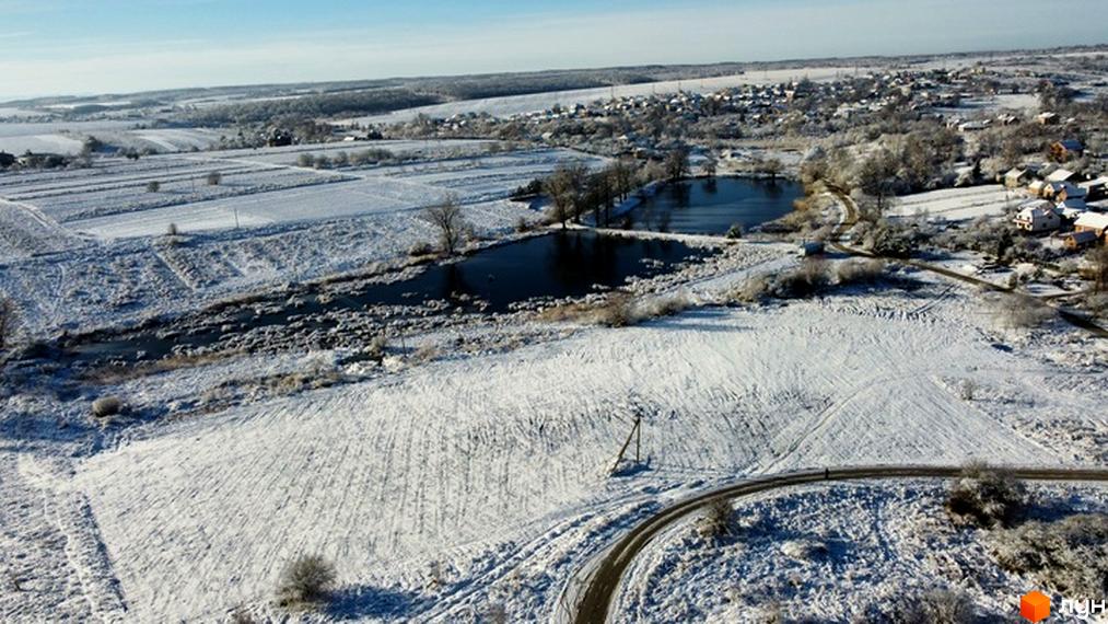 КМ Impulse: вид на житловий комплекс із засніженими полями та озером. Опис прибудинкової території з дорогою та деревами.