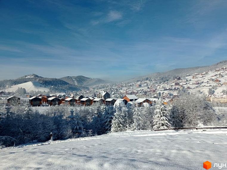 Котеджне містечко Phoenix Relax Park: будинки з темними дахами серед засніжених ялинок та гірських схилів.