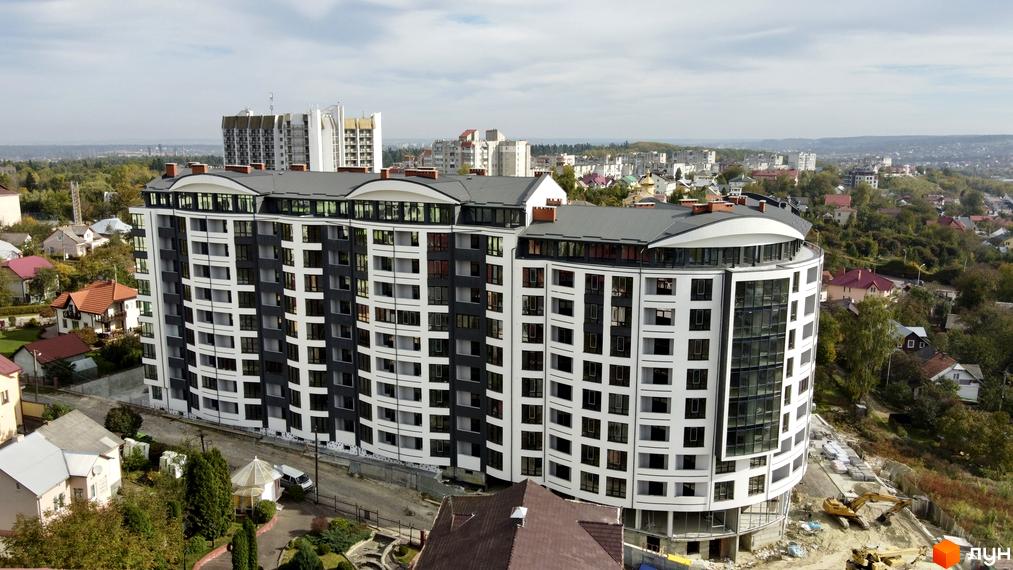 Зображення фасаду та прибудинкової території Житлового комплексу Трускавецька Фортеця. Багатоповерхова будівля з великою кількістю вікон.