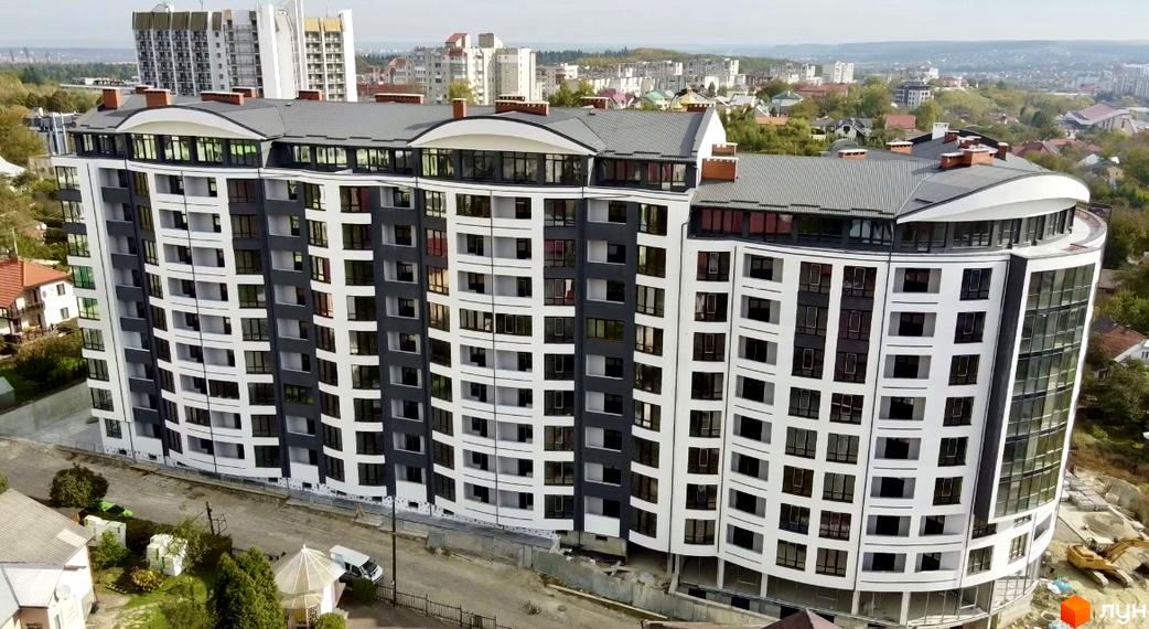 Зображення фасаду Новобудови Трускавецька Фортеця. Багатоповерхова будівля з великою кількістю вікон та сіро-білим оздобленням.