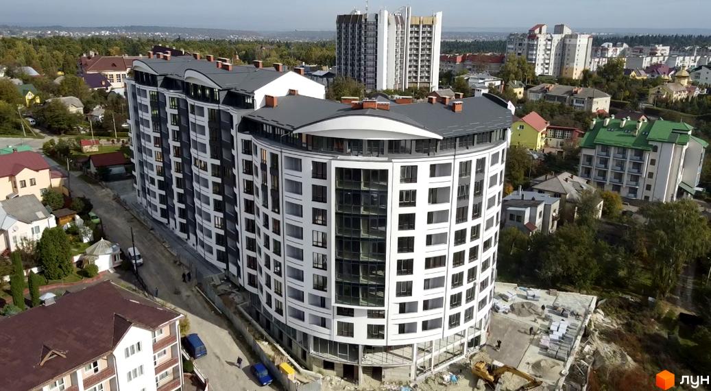 Зображення Житлового комплексу Трускавецька Фортеця. Багатоповерховий будинок з великими вікнами та заокругленим фасадом, видно прибудинкову територію.