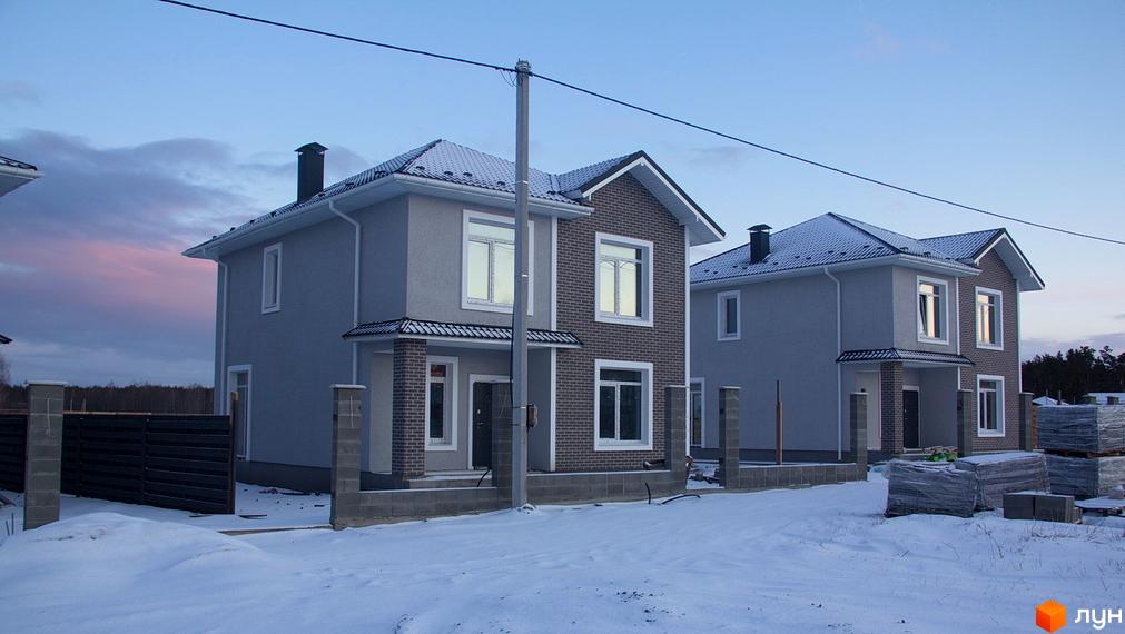 Двоповерхові будинки з сірим фасадом та цегляними елементами на вулиці Василя Стуса. Навколо засніжена територія з парканом та будівельними матеріалами.