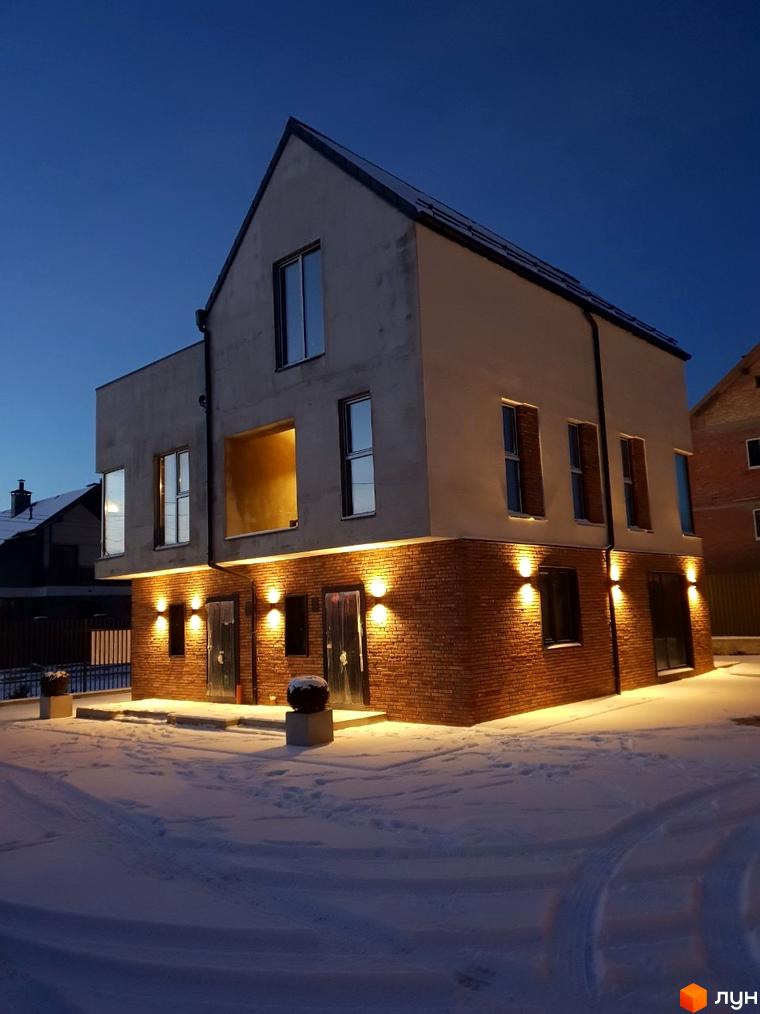 Сучасні таунхауси DOMA NOVA з цегляним фасадом та великими вікнами взимку. Територія навколо будівель вкрита снігом, освітлена вуличними ліхтарями.