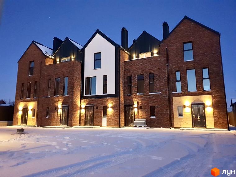 Таунхауси DOMA NOVA у вечірній час, фасад з червоної цегли, освітлення фасаду, засніжена прибудинкова територія.