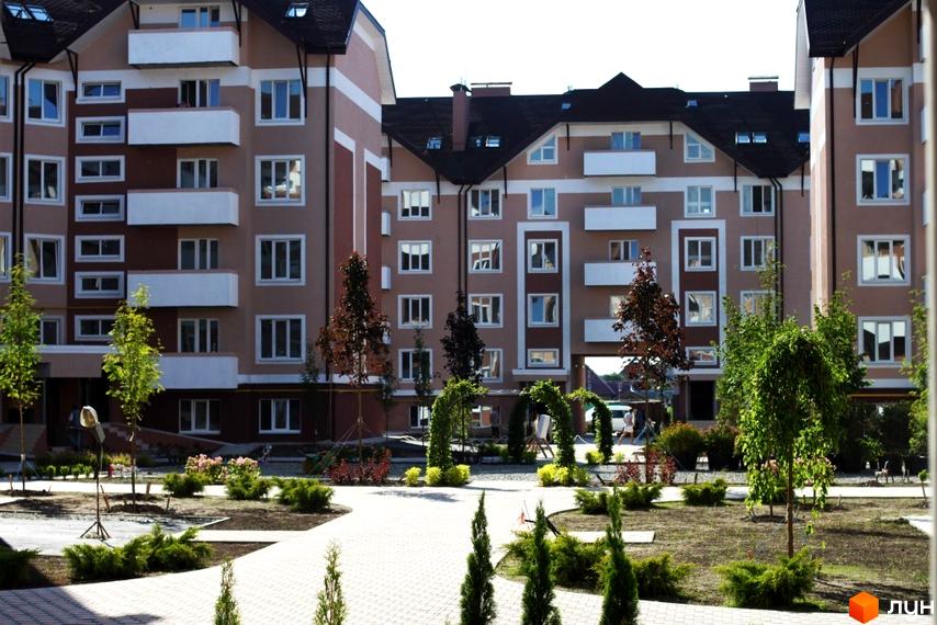 Зовнішній вигляд житлового комплексу Новатор з сучасними балконами та прибудинковою територією з зеленими насадженнями.