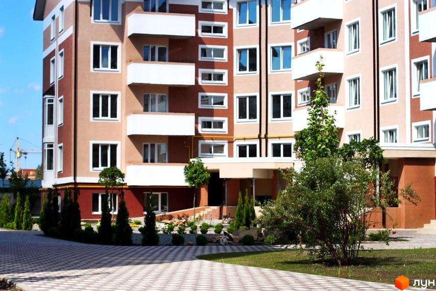 Житловий комплекс Новатор: багатоповерховий будинок з балконами та вікнами, прибудинкова територія з деревами та доріжкою.