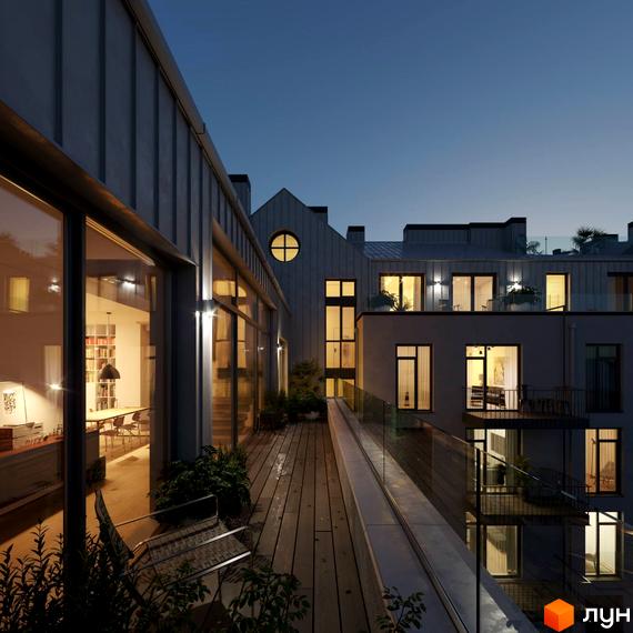 Вечірній вигляд на фасад Житлового комплексу Княжий Холл з великими вікнами, круглим вікном та терасою з дерев'яним настилом.