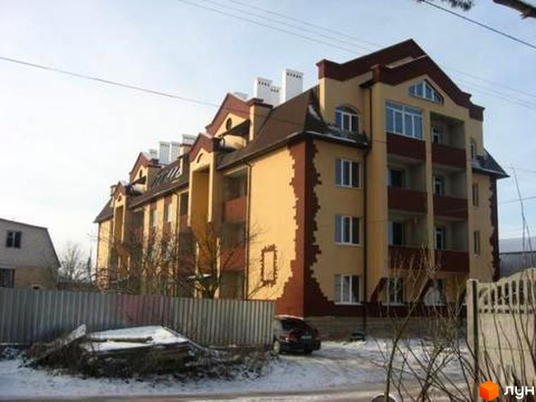 Новобудова на вул. Першотравнева, 11: багатоквартирний будинок світло-жовтого кольору з коричневими акцентами та балконами. Прибудинкова територія засніжена.