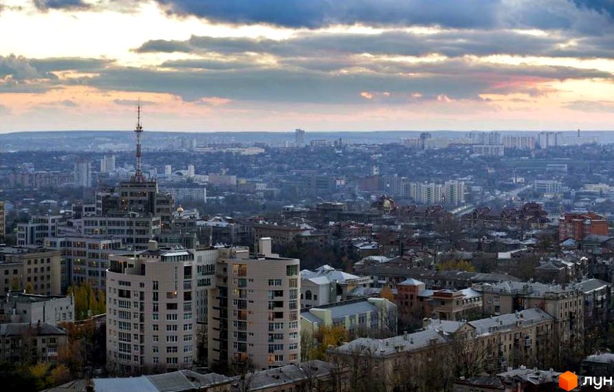 Панорамний вид на житловий комплекс Схід-Захід з сучасними будівлями та міським пейзажем на фоні хмарного неба. Опис новобудови для просування сайту.