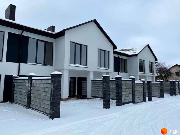 Двоповерхові будинки з великими вікнами та темними дахами, огороджені парканом з бетонних блоків та стовпів. Новобудова на вул. Мельника, 25.