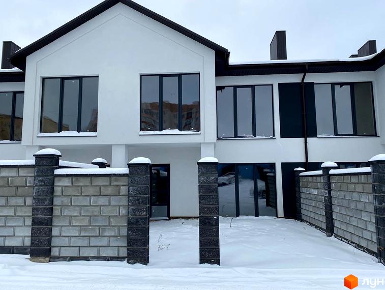 Зовнішній вигляд новобудови на вул. Мельника, 25, взимку. Будинок має білий фасад, великі вікна та огороджену територію з парканом.