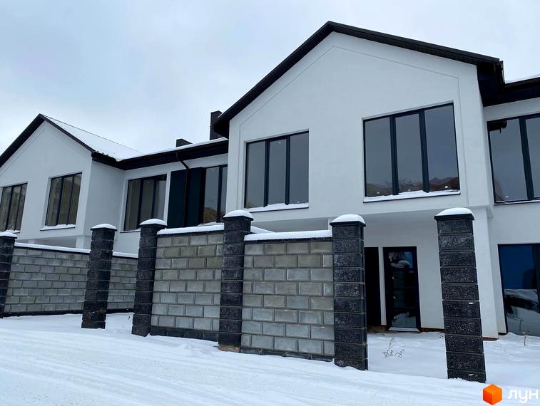 Зовнішній вигляд новобудови на вул. Мельника, 25, з білою фасадною штукатуркою та великими вікнами. Навколо будинку огороджена територія з цегляною огорожею та стовпами.