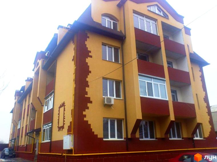 Житловий комплекс на вул. Першотравнева, 11 з яскравим фасадом та балконами. Прибудинкова територія облаштована для комфортного проживання.