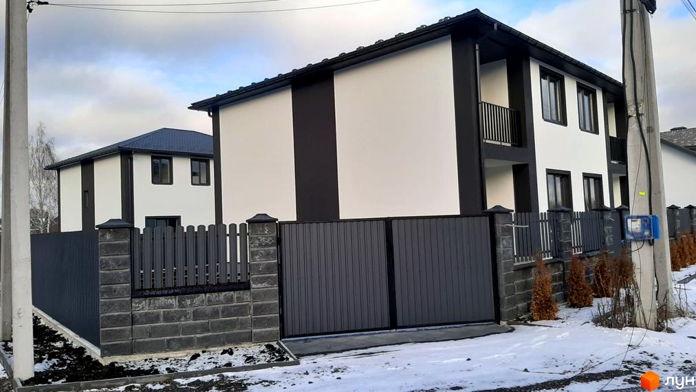 Новобудова Сонячний дім 3 з біло-темним фасадом та сірим парканом. Прибудинкова територія з деревами та снігом.