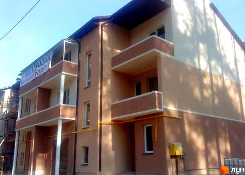 Триповерхова новобудова з двоколірним фасадом та балконами. На фасаді видно жовті газові труби та поштову скриньку.