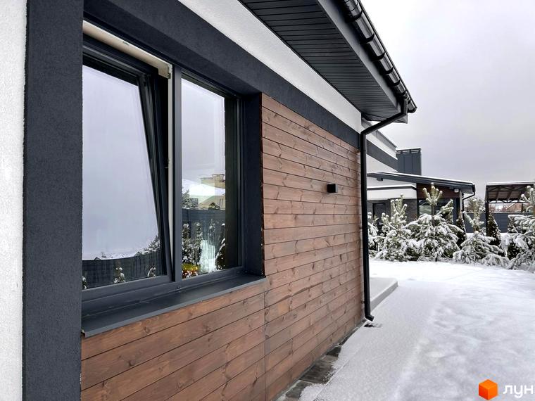 Зовнішній вигляд будинку з дерев'яним фасадом та великими вікнами на вулиці Мазепи. Навколо будинку засніжена територія з ялинками.