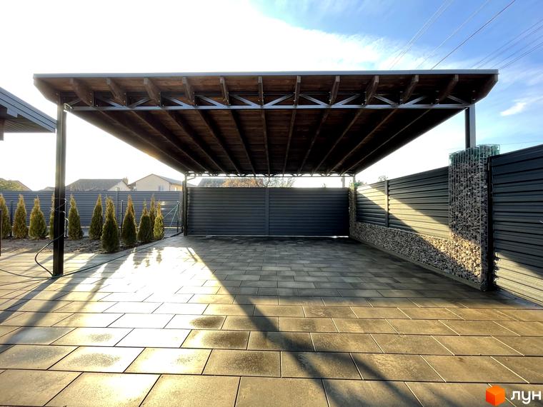 Навіс для авто з дерев'яною обробкою та бруківка на подвір'ї житлового комплексу по вул. Мазепи. Прибудинкова територія має огорожу з габіонами.