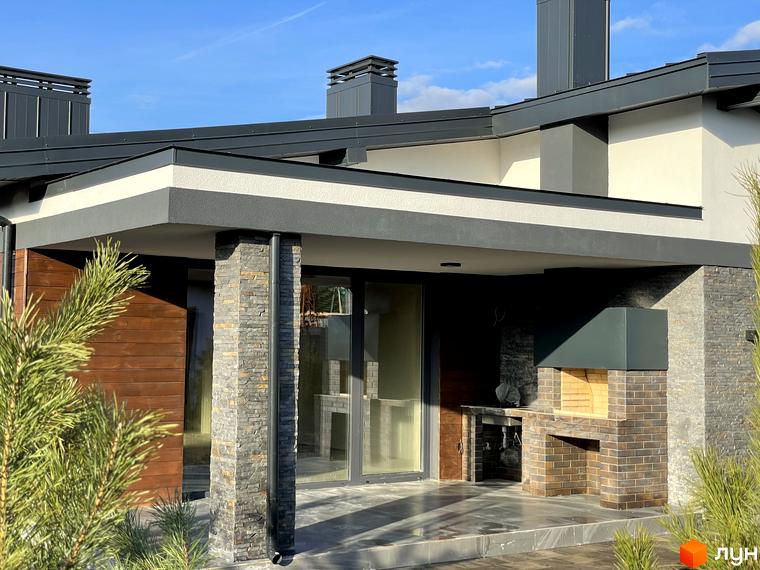 Сучасний житловий комплекс на вулиці Мазепи з цегляним барбекю та дерев'яними елементами фасаду. Навколо зелені насадження та блакитне небо.