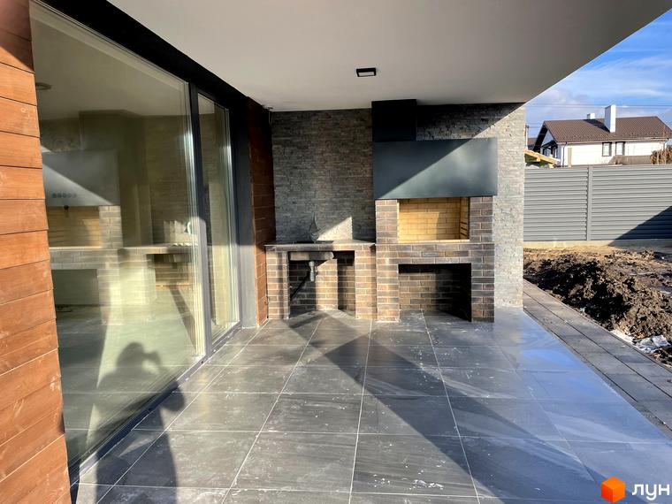 Зовнішній вигляд будинку новобудови на вул. Мазепи: тераса з великими скляними дверима та вбудованою зоною барбекю.