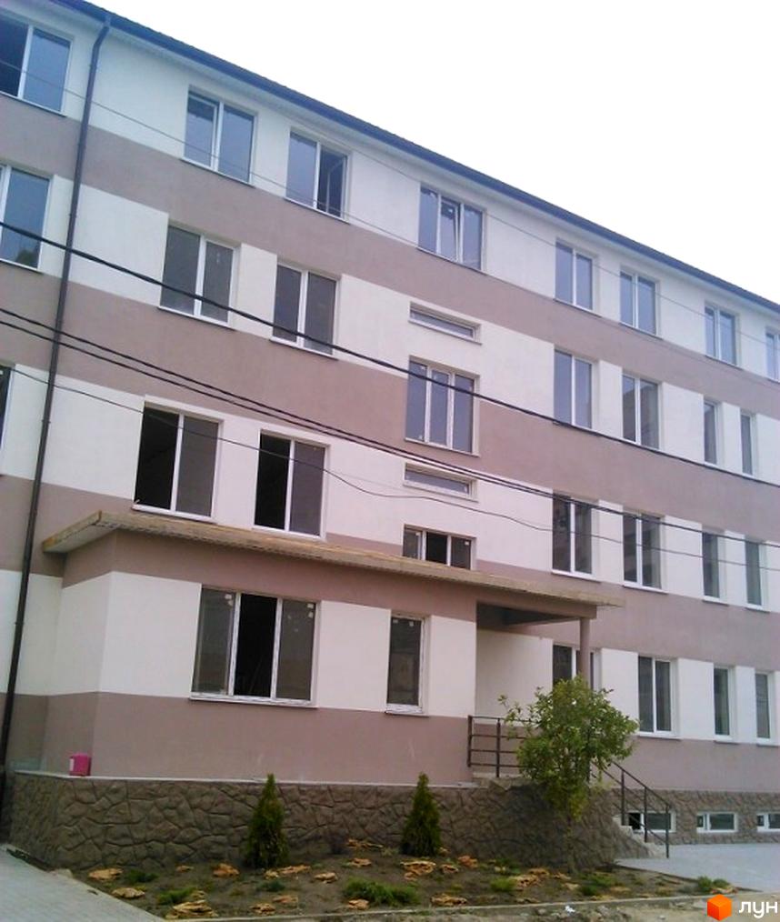 Зовнішній вигляд Житлового комплексу Софіївський дом. Багатоповерхова будівля з оздобленням у світлих тонах та великими вікнами, озеленена прибудинкова територія.