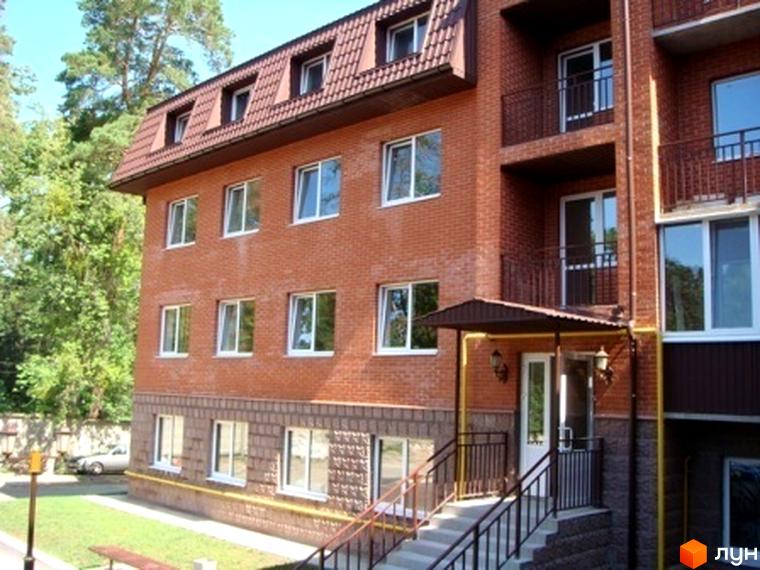 Зовнішній вигляд будинку ЖК Green Park з червоної цегли, прибудинкова територія з зеленими насадженнями.