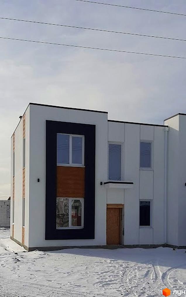 Котеджне містечко Holland Park: білий двоповерховий будинок з чорними та коричневими акцентами на фасаді, оточений снігом.